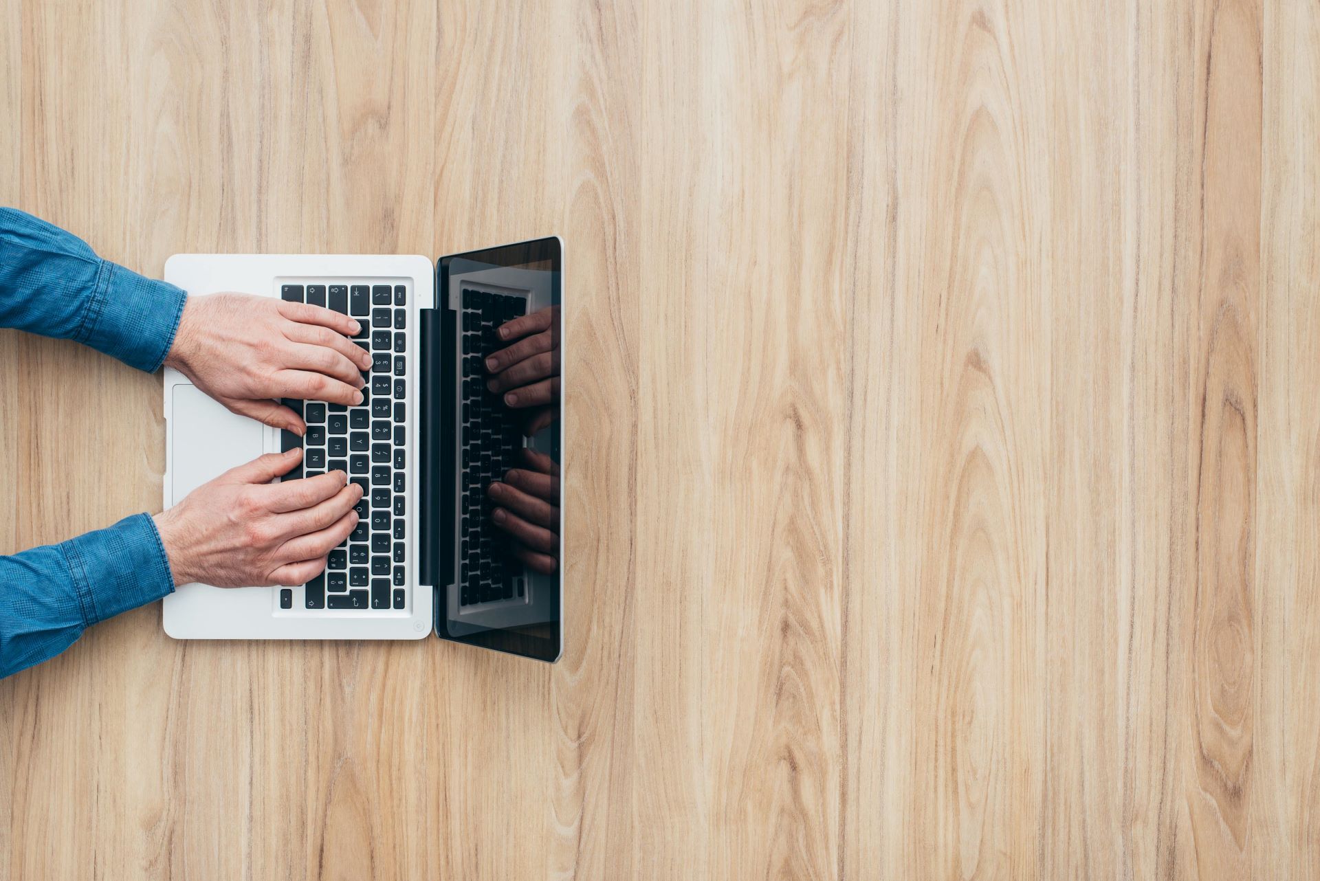Bovenaanzicht van iemand die werkt achter zijn laptop