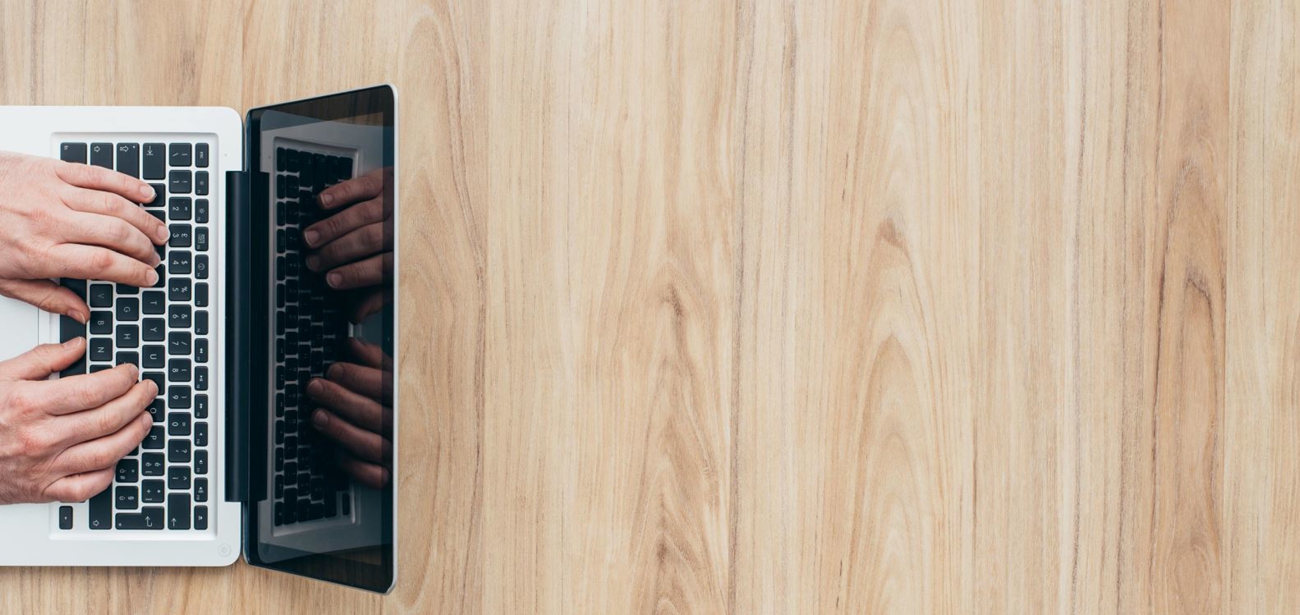 Bovenaanzicht van iemand die werkt achter zijn laptop