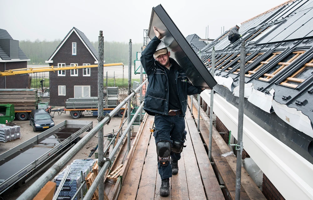 Installateur die zonnecollector op het dak tilt in Almere
