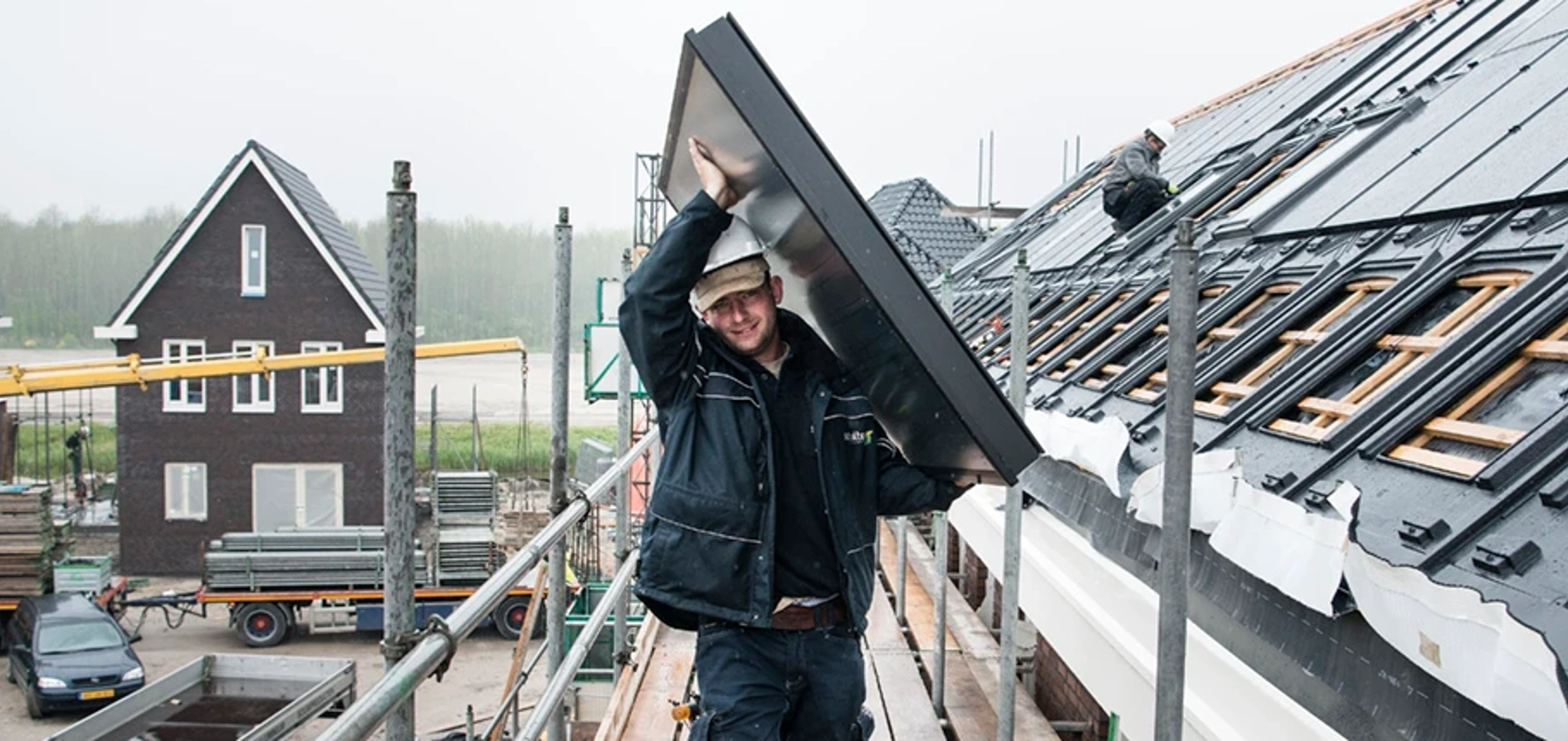 Installateur die zonnecollector op het dak tilt in Almere