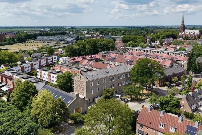 Zijaanzicht van een wijk met huizen en gebouwen met op de gebouwen PVT-panelen van HR energy op het dak