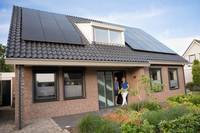 Man en vrouw voor hun huis met op het dak PVT panelen van HR energy