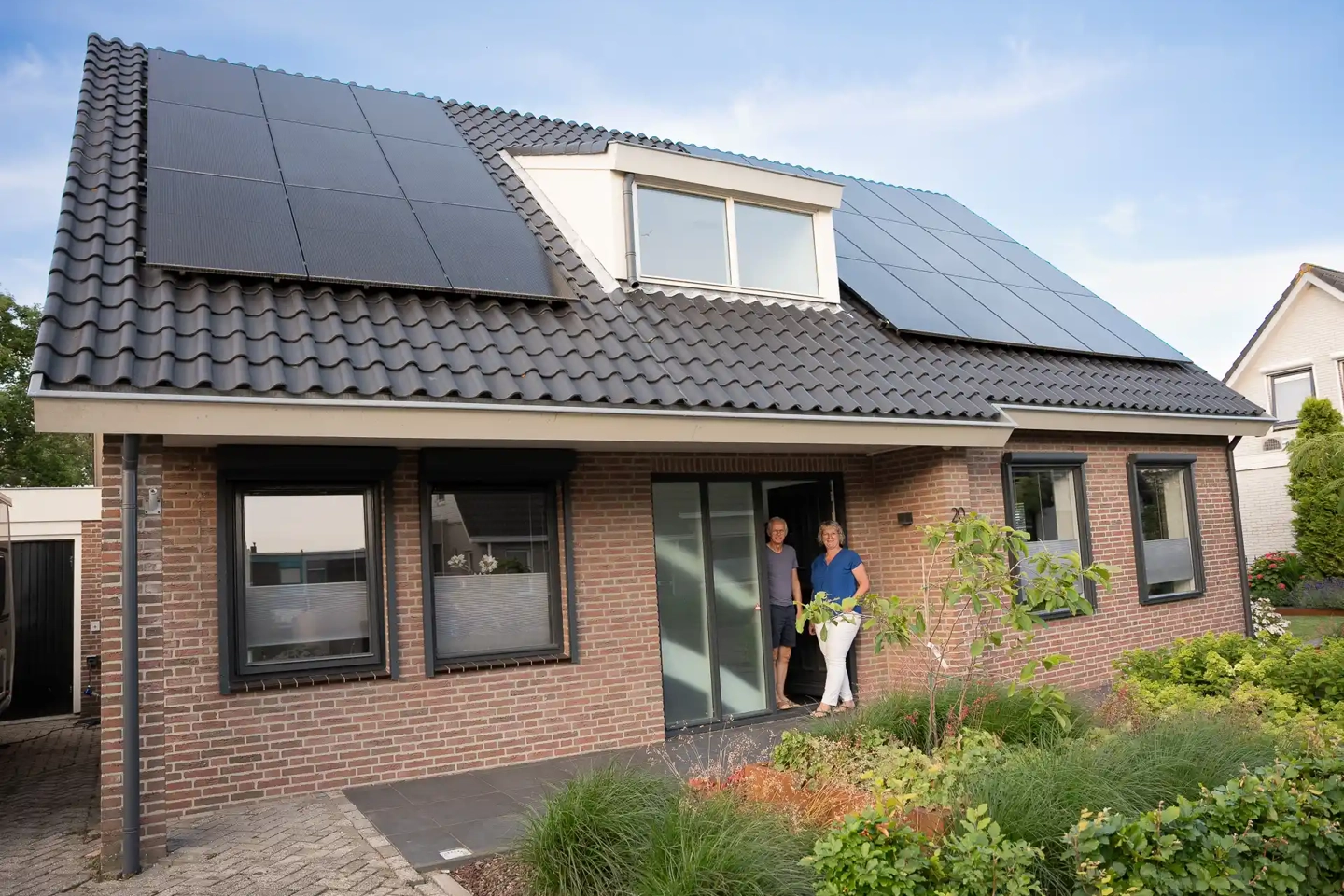 Man en vrouw bij woning met PVT-panelen en warmtepomp in Naaldwijk