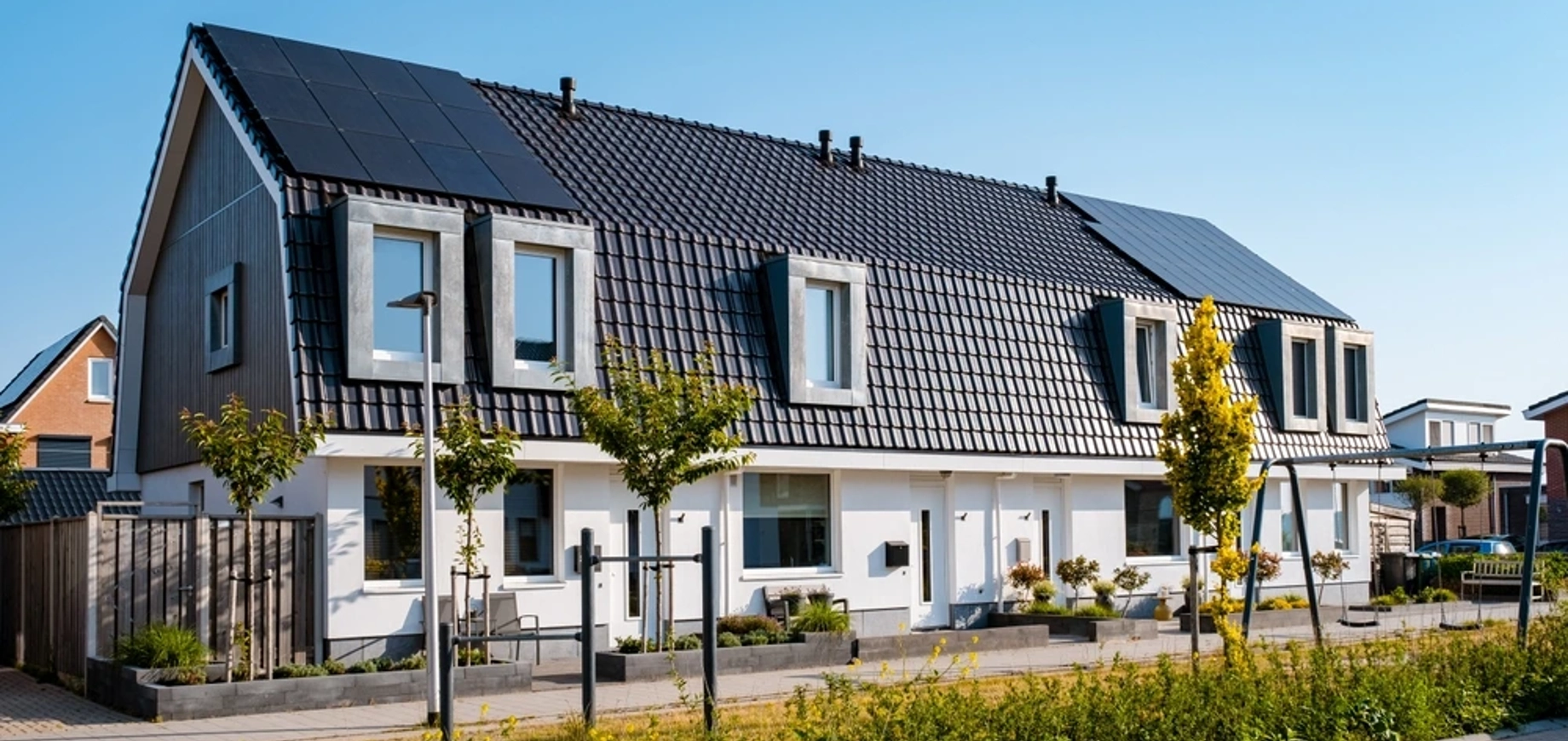 Rij huizen met bomen en zonnepanelen op het dak in een duurzame wijk