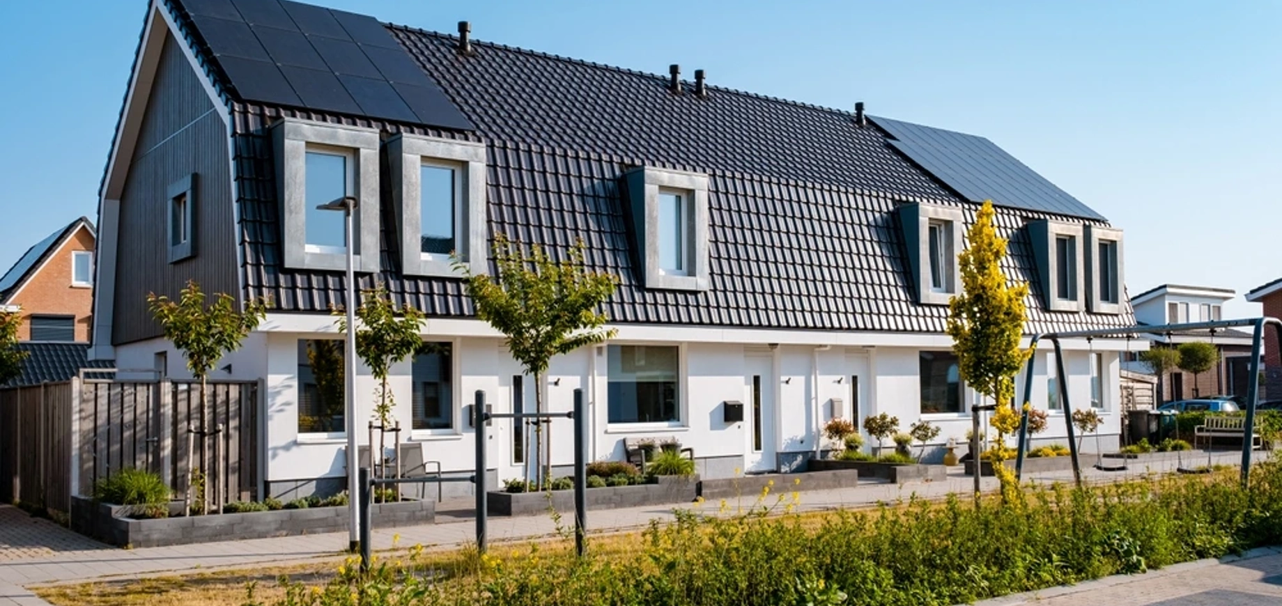 Rij huizen met bomen en zonnepanelen op het dak in een duurzame wijk