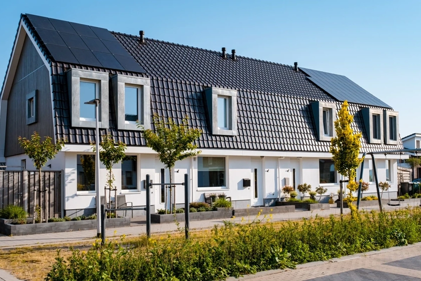 Rij huizen met bomen en zonnepanelen op het dak in een duurzame wijk